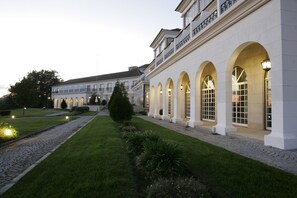 Un edificio grande y elegante con ventanas arqueadas y un césped cuidado.