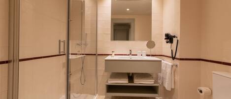 Une salle de bain moderne avec une douche à parois de verre, un lavabo avec un miroir au-dessus et des toilettes.
