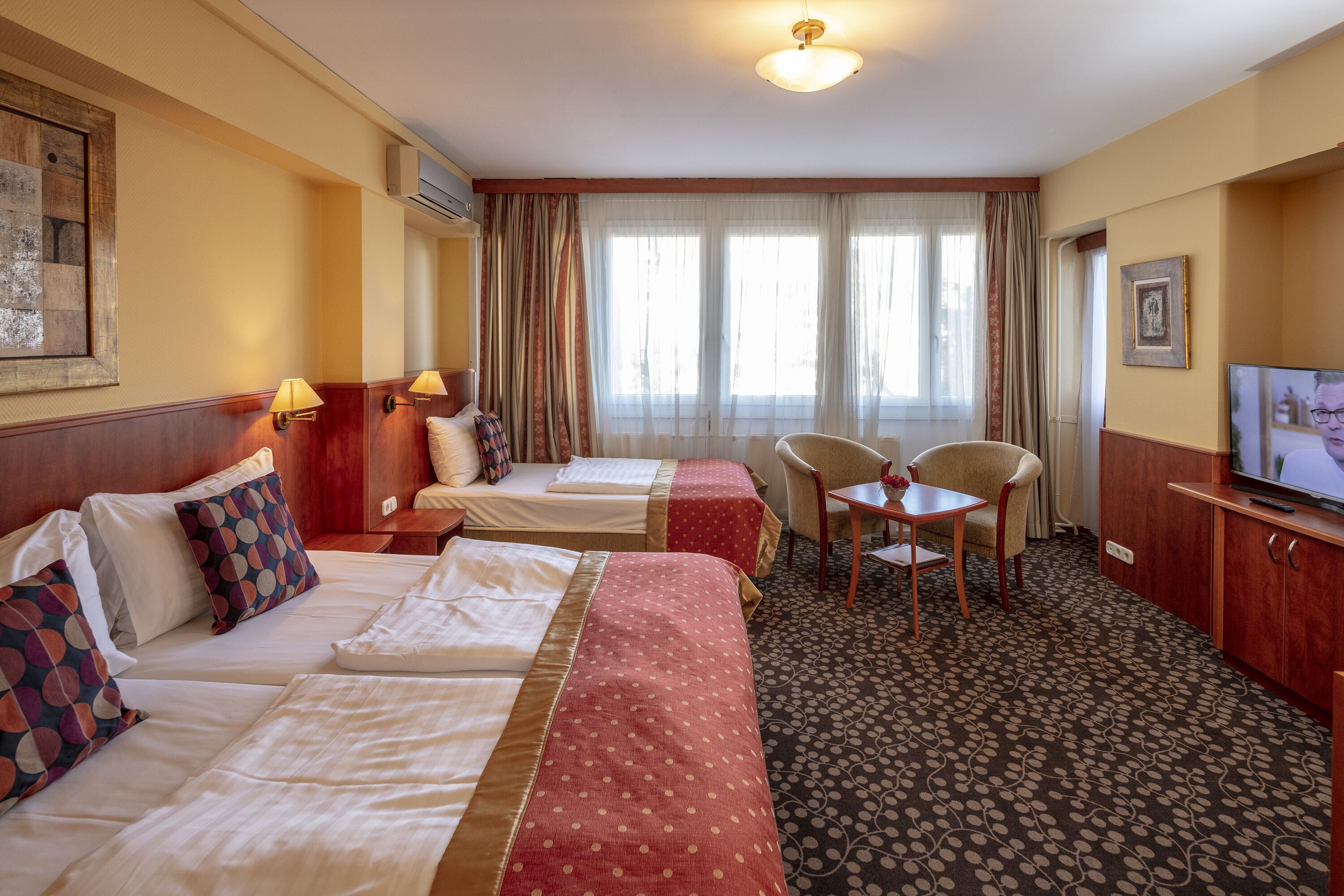 A hotel room with two beds, a television, a desk, and a chair.