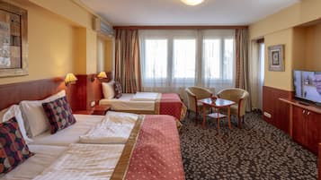 A hotel room with two beds, a television, a desk, and a chair.