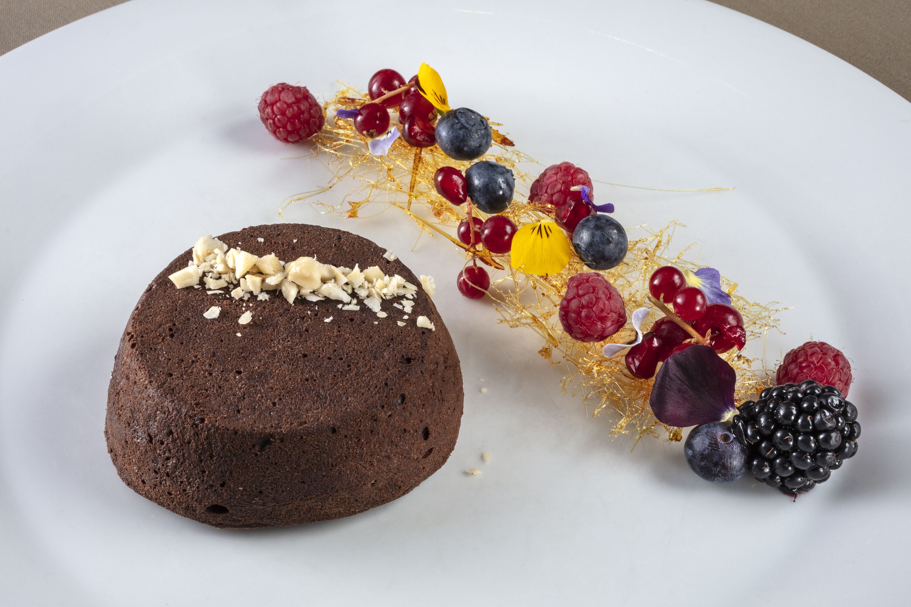 Un postre con pastel de chocolate y una variedad de bayas sobre un plato blanco.