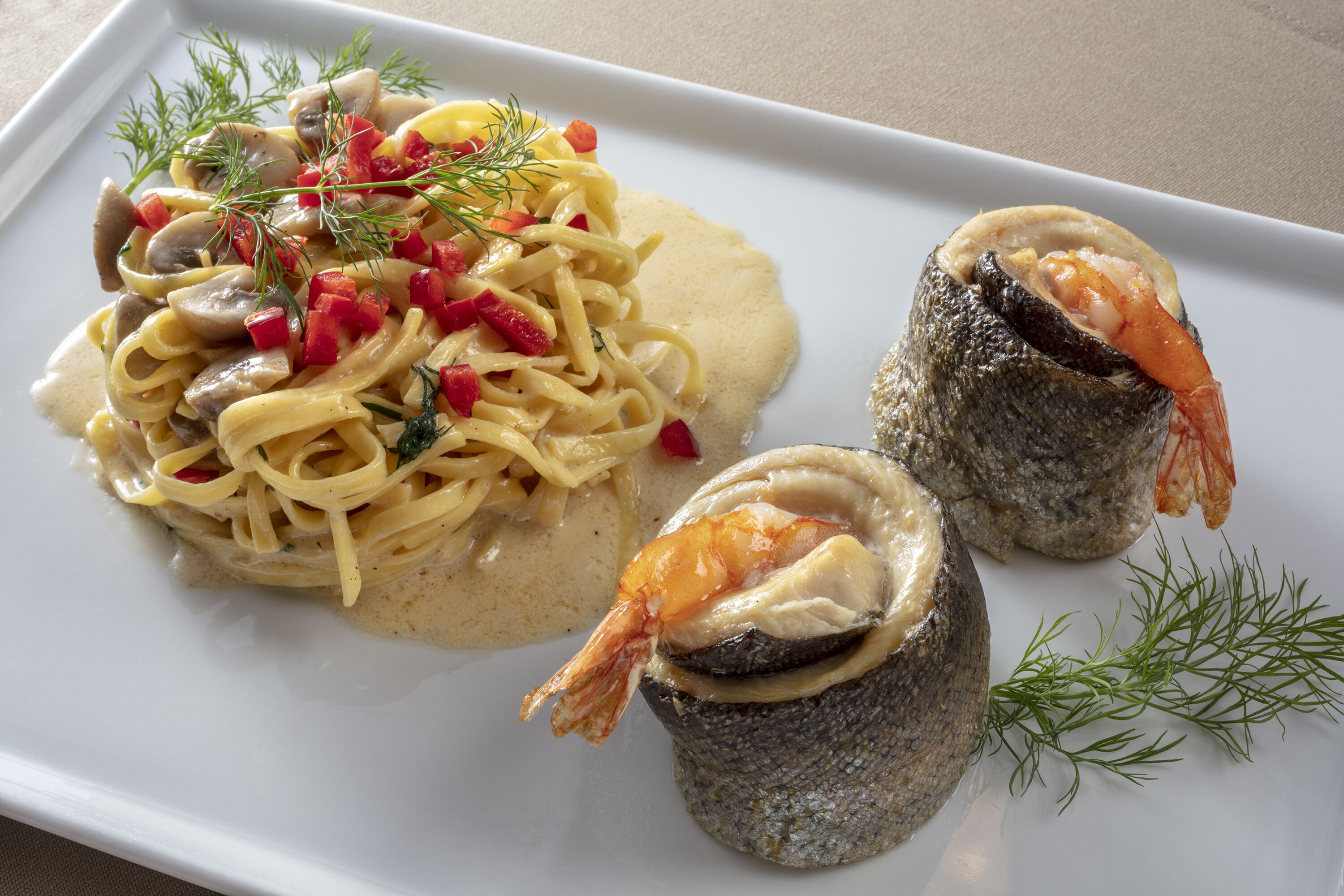 Eine Pasta-Tellerei mit Garnelen und einem Fischkopf.