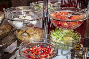 A buffet with various food items including fruits, vegetables, and other dishes. - Hotel Charles (Budapest)