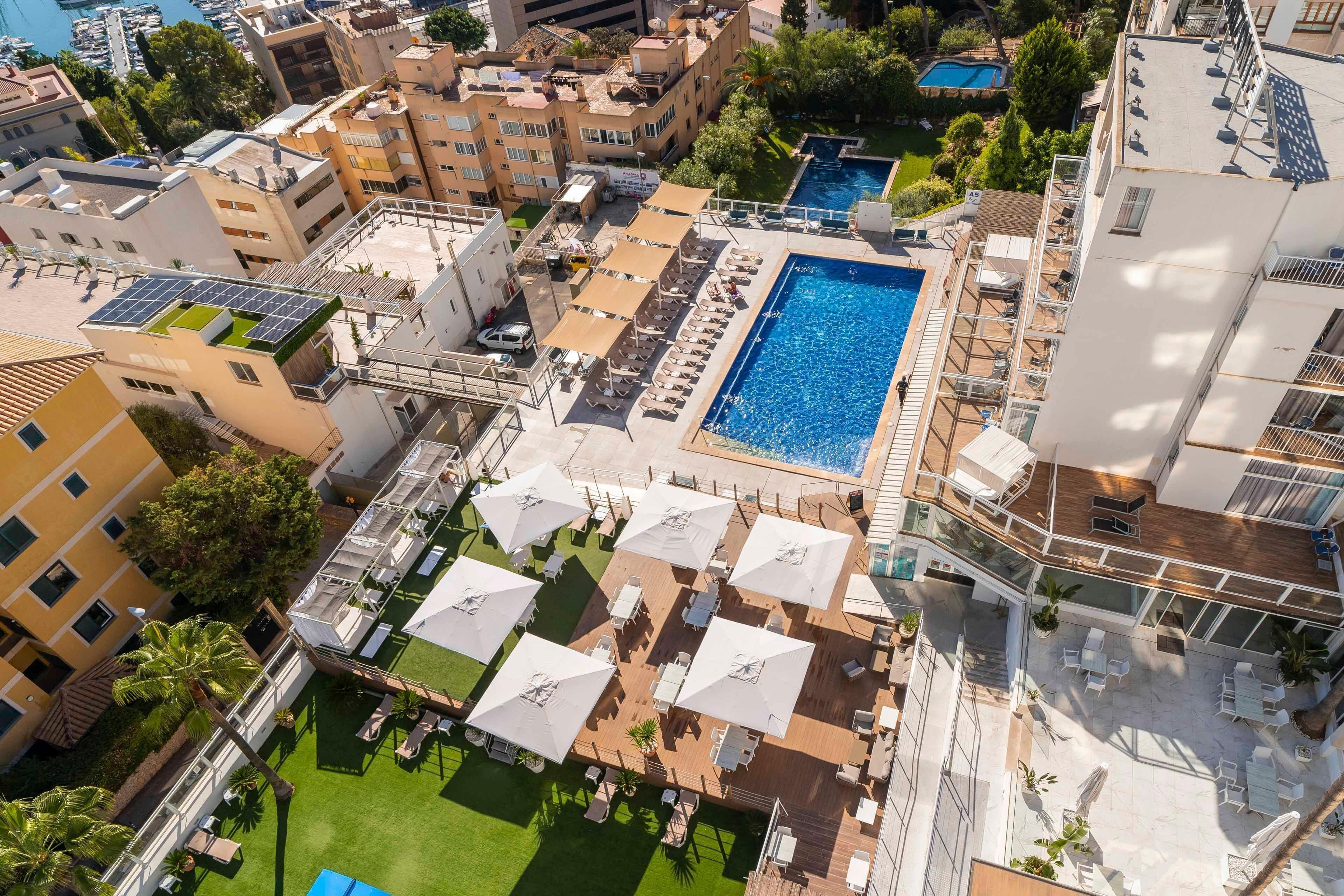 Vista aérea de un hotel con piscina, mobiliario exterior y terraza en la azotea.