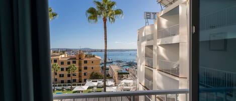 A balcony with a view of a marina, palm trees, and buildings.