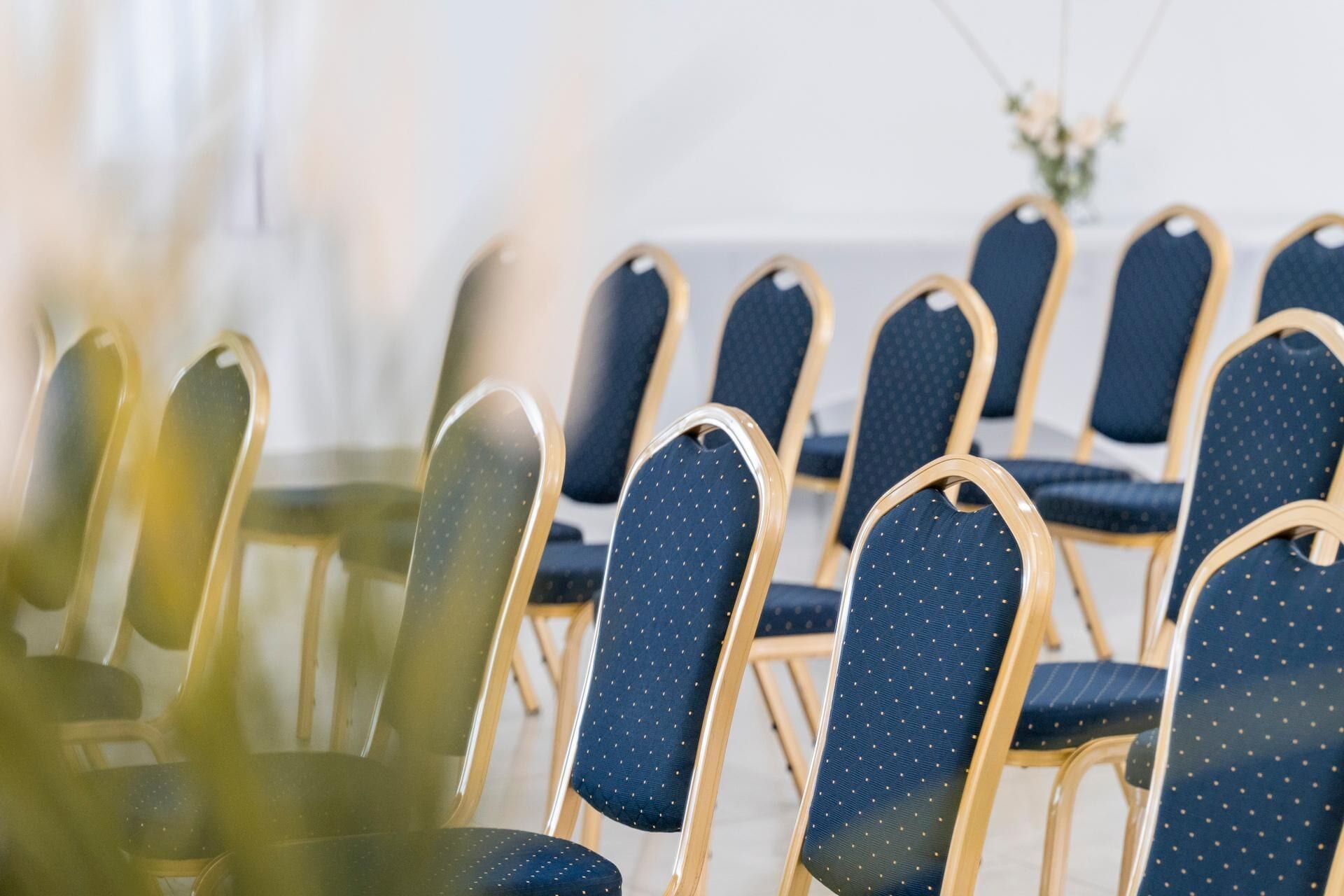 Rows of chairs with dark blue upholstery and gold frames, arranged in a conference room setting.