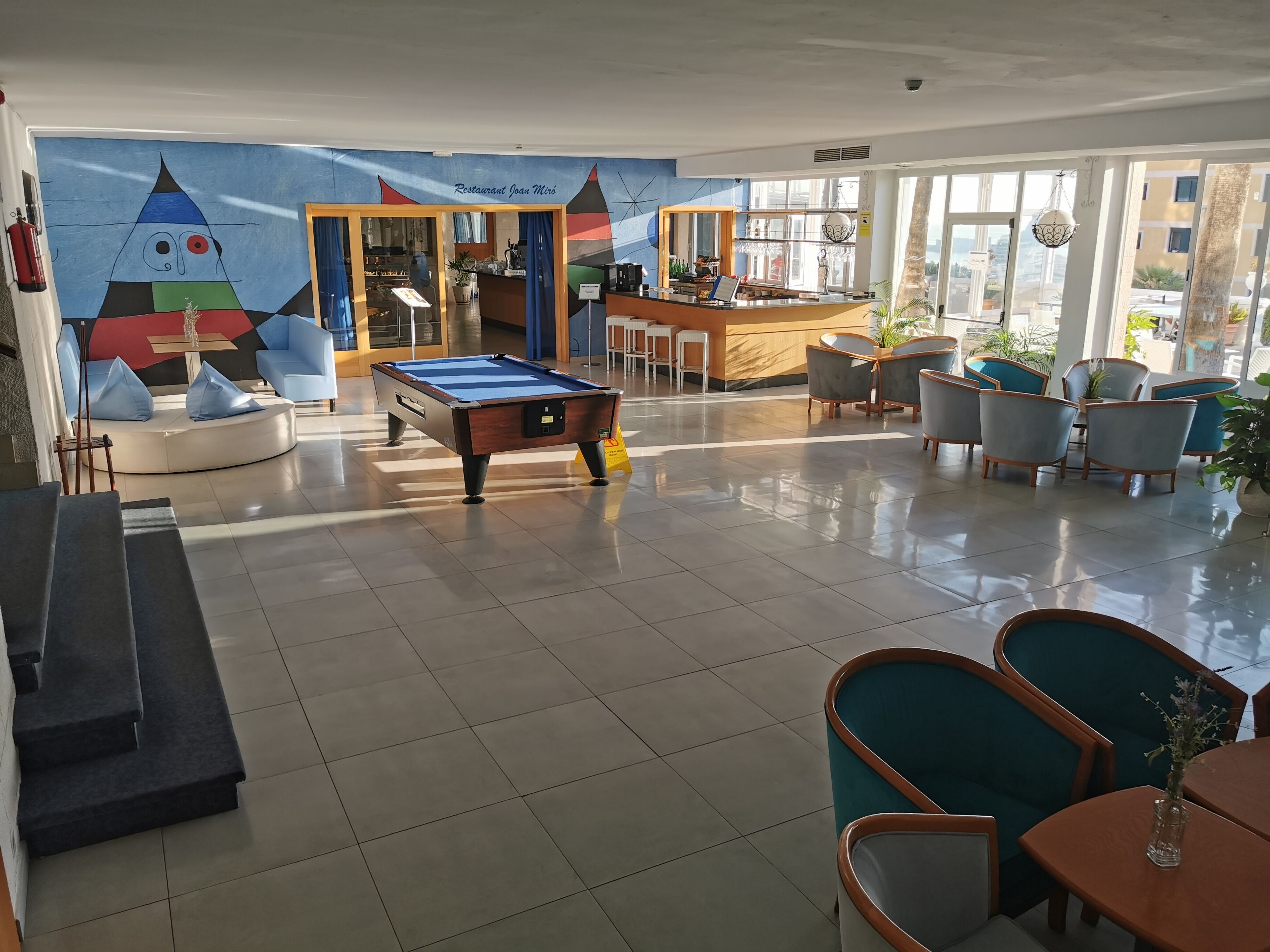 A pool table in a well-lit indoor space with a bar area and seating.