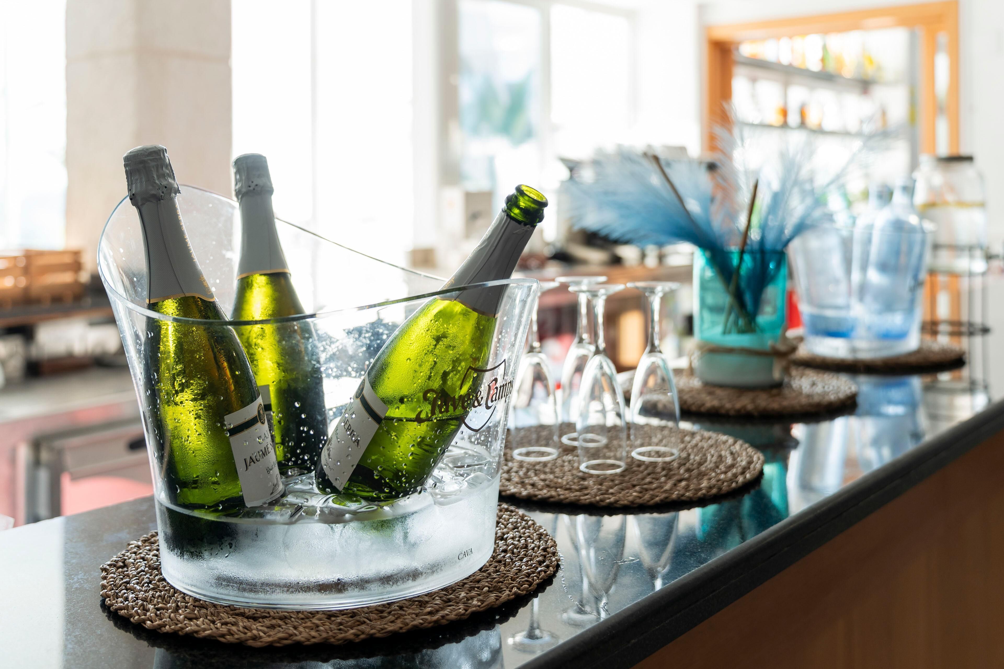 A bar area with a glass container holding champagne bottles and glasses on coasters.
