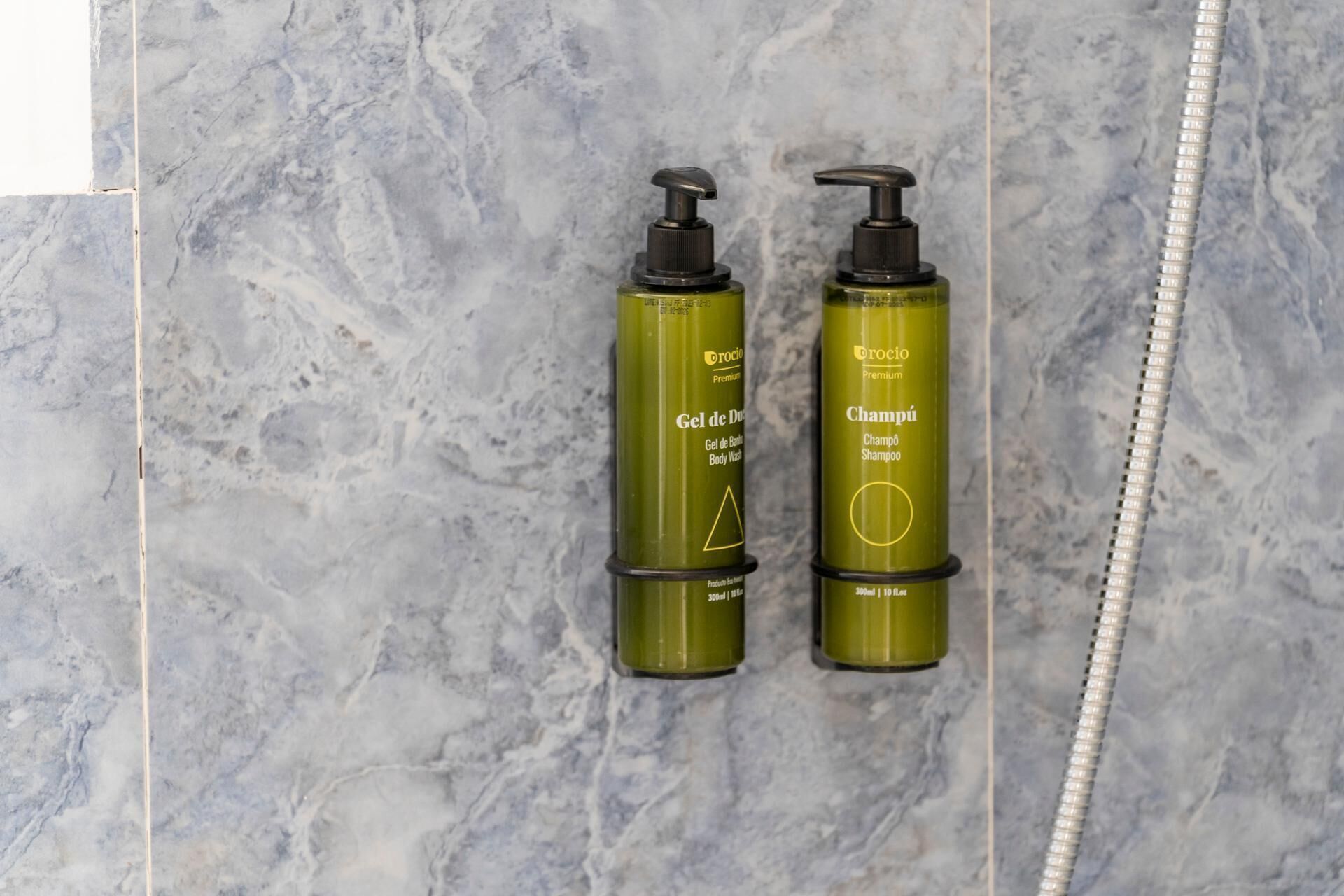 Two green bottles of OROCIO Premium body wash and shampoo on a marble surface.
