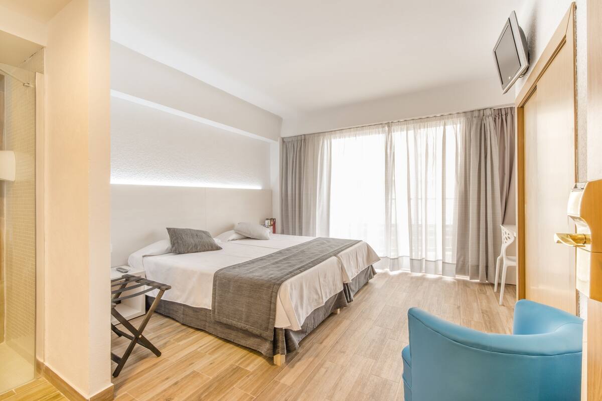 Une chambre d’hôtel moderne, dotée d’un grand lit, d’un bureau et d’une chaise.
