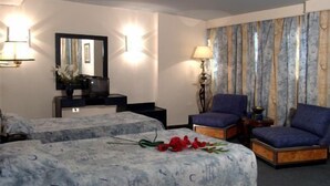 Habitación de hotel con dos camas, un escritorio, una silla, una lámpara y un espejo.