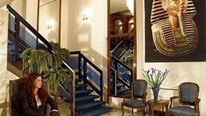 Un vestíbulo con una escalera, un gran artefacto egipcio y una zona de estar.
