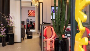 A modern interior with a cactus plant, a red chair, and a black sofa. - Hôtel du Triangle d'Or (Paris)