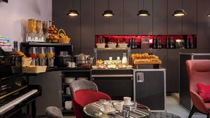 A modern bar area with a piano, seating, and a variety of food and drink options. - Hôtel du Triangle d'Or (Paris)