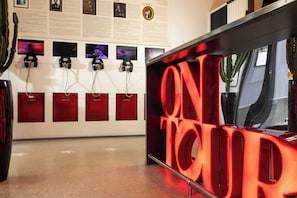 A room with a red illuminated sign, a wall with framed photos, and a cactus plant. - Hôtel du Triangle d'Or (Paris)