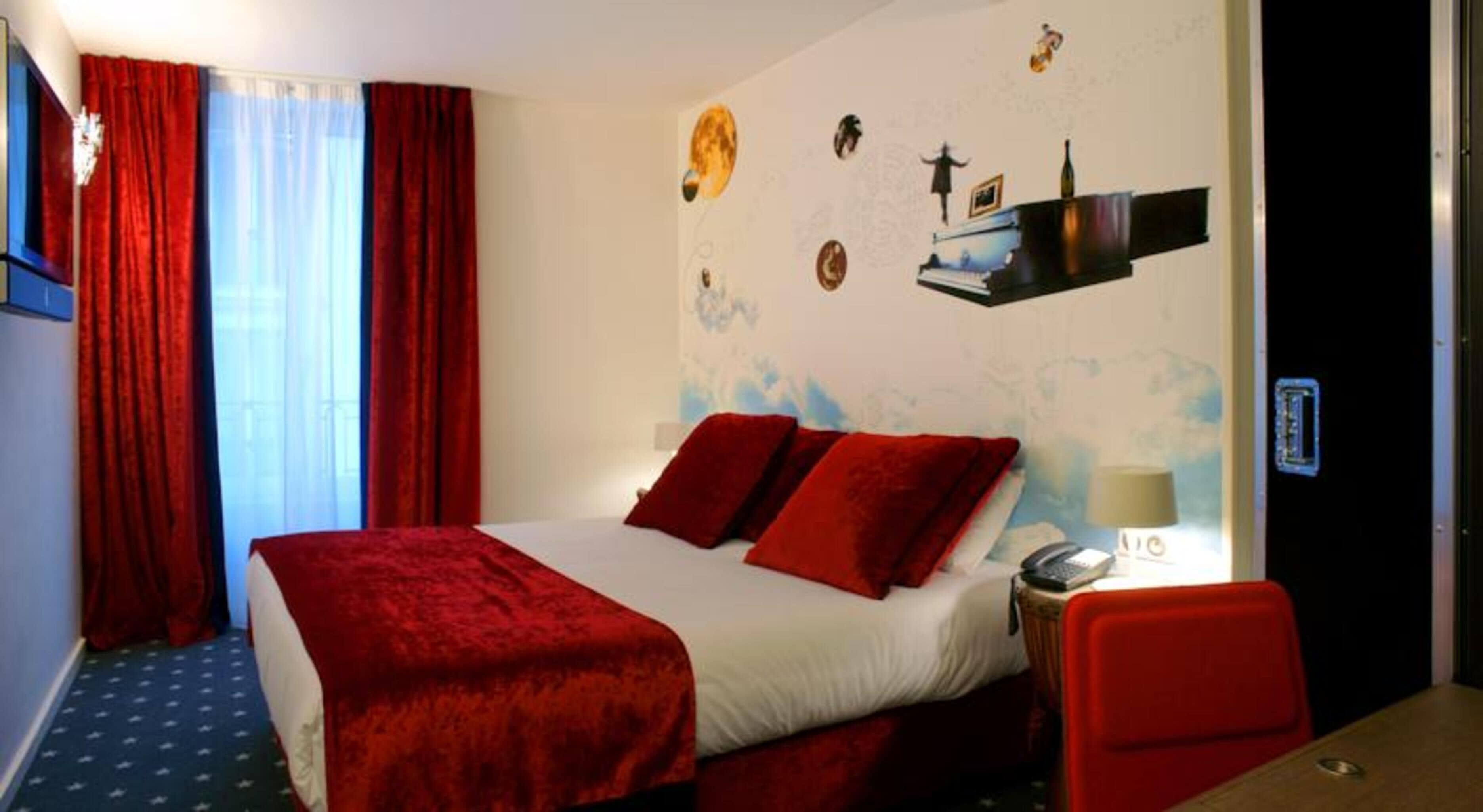 A hotel room with a bed, red curtains, a desk with a chair, a wall clock, and a window with curtains.