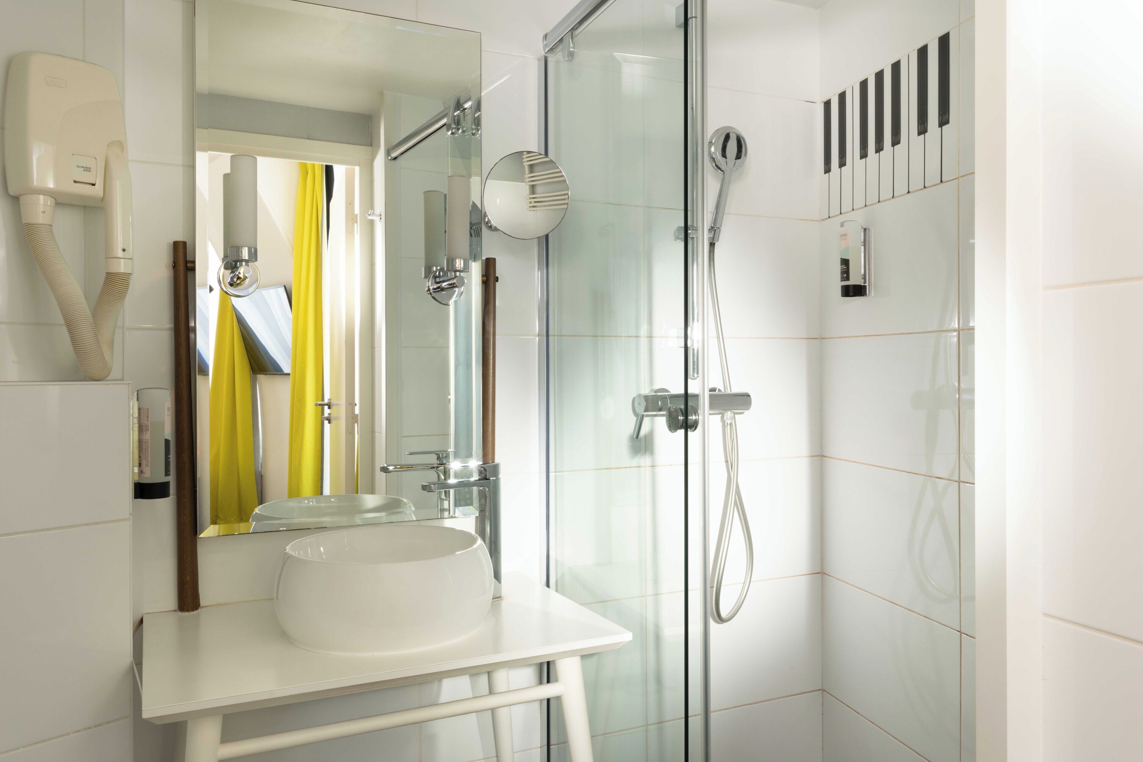 Ein modernes Badezimmer mit einer Duschkabine aus Glas, einem weißen Waschbecken und einem Spiegel.