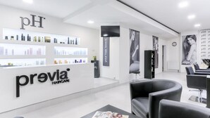 A modern hair salon interior with a reception area, salon chairs, and a display of hair care products. - Hotel Globus (Prague)