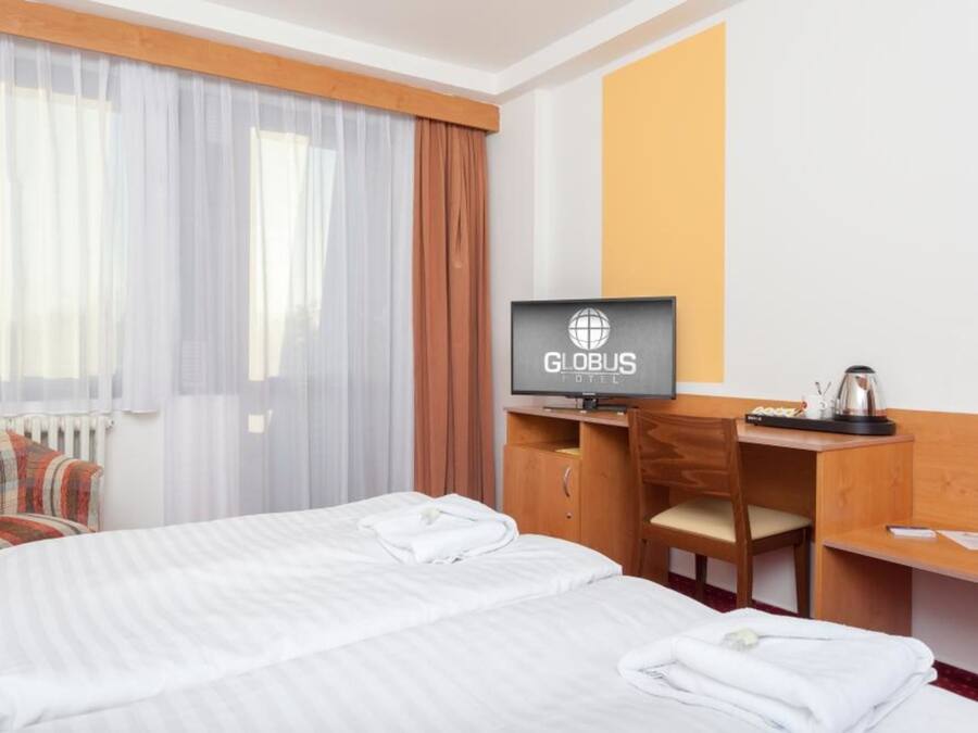 Ein Hotelzimmer mit einem Bett, einem Schreibtisch mit Fernseher und einem Sessel.