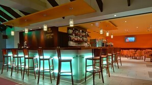 A bar area with a counter, bar stools, and a television screen. - Hotel Globus (Prague)