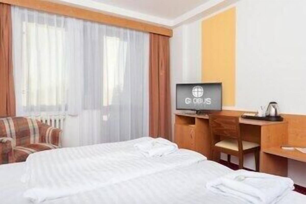 A hotel room with two beds, a television, a desk, and a chair.