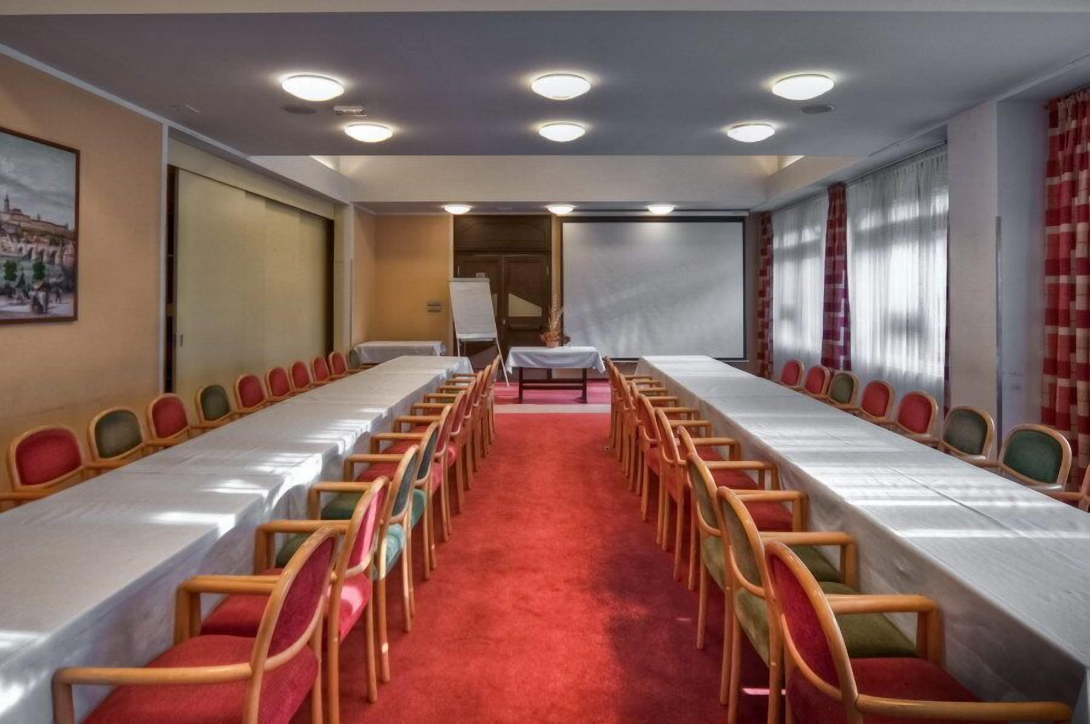 A conference room with a long table and chairs, a red carpet, and a whiteboard.