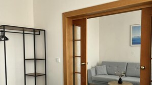Un dormitori amb un llit, un armari, una porta que dóna a una zona d'estar amb un sofà i una taula.