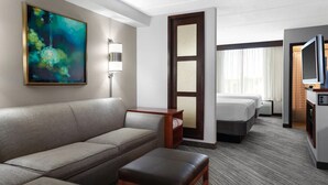 Une chambre d’hôtel avec un canapé, une petite table, une télévision et un lit.