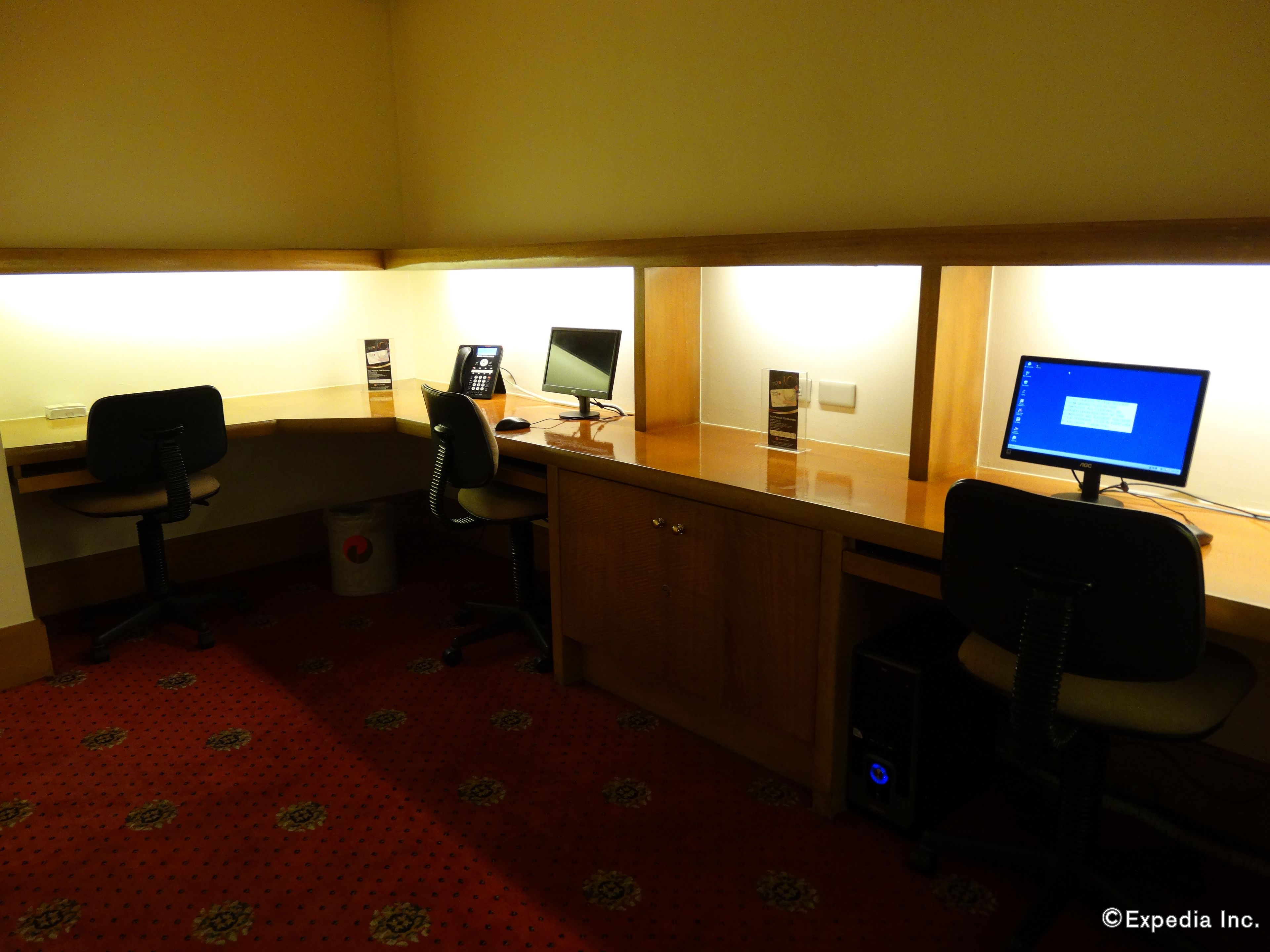 Una habitación de hotel con un escritorio, dos sillas, una computadora y un teléfono.