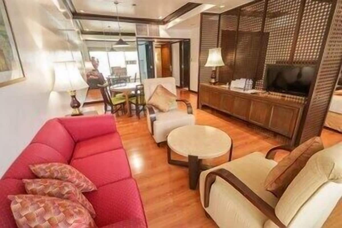 A modern living room with a red sofa, a beige sofa, a round coffee table, and a TV on a wooden cabinet.