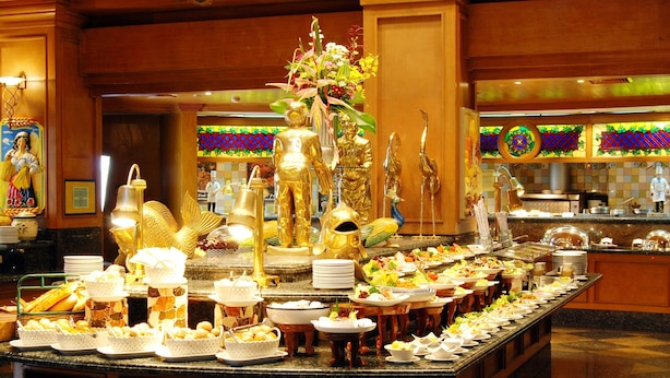 Un bufé con diversos alimentos y estatuas doradas decorativas.