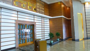 Un moderno vestíbulo de hotel con un mostrador de recepción, paneles de madera y plantas en macetas.