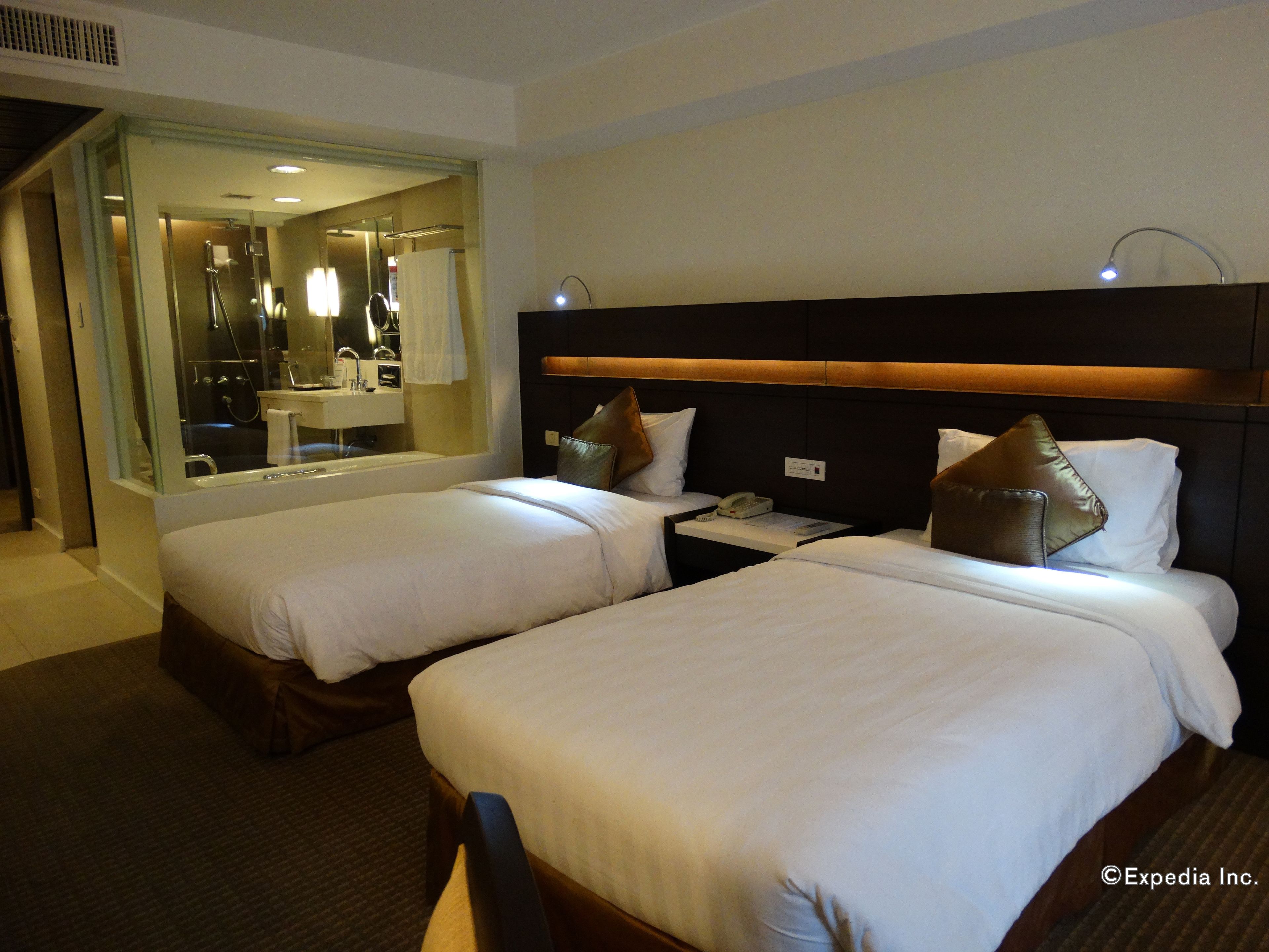 A hotel room with two beds, a bathroom, and a mirror.