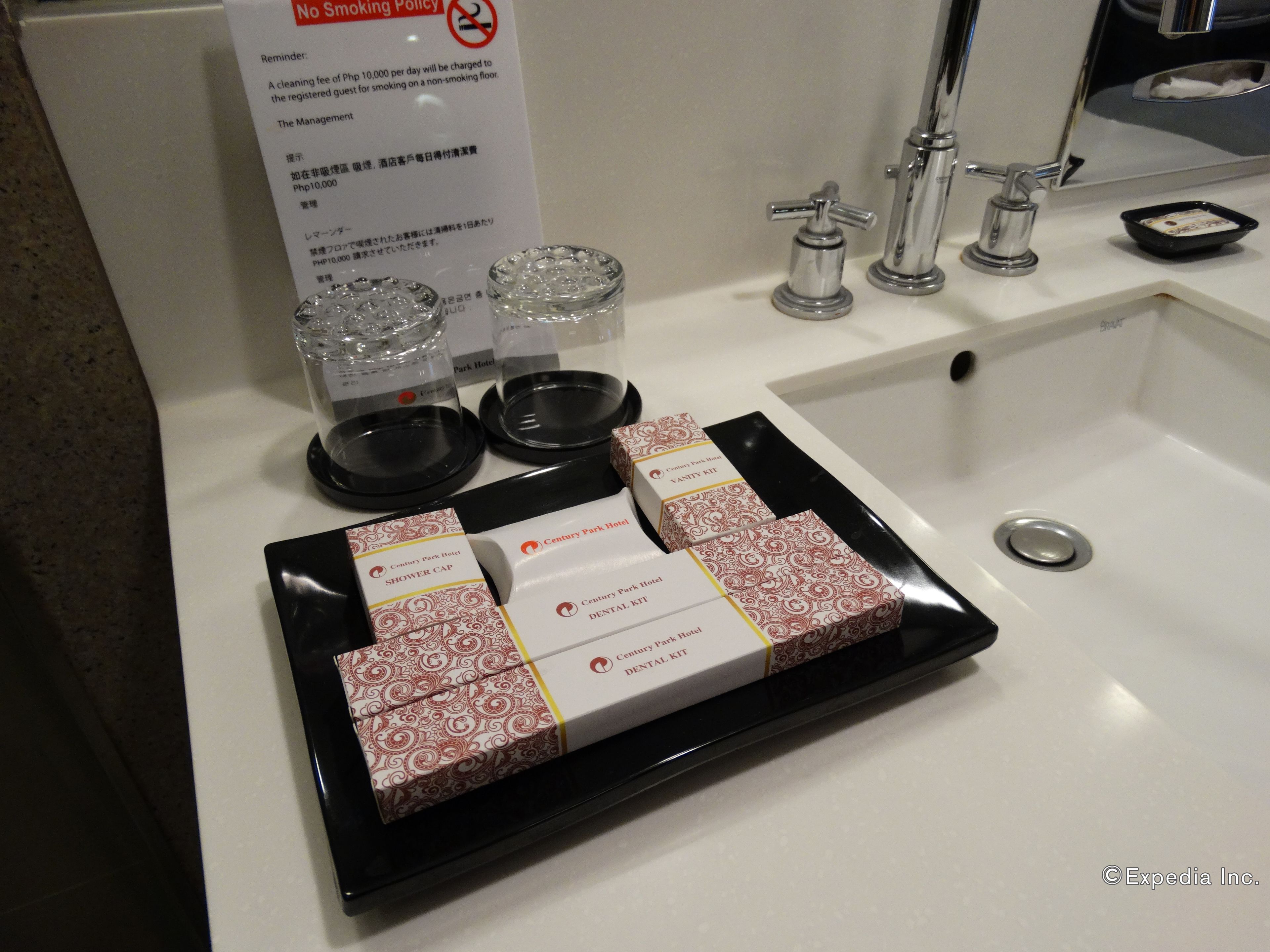 Un lavabo de salle de bain d’hôtel avec des articles de toilette et un panneau indiquant qu’il est interdit de fumer.
