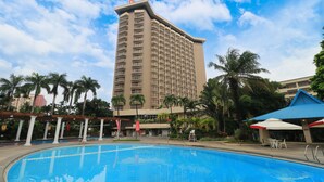 Un hotel con piscina, palmeras y un edificio de techo azul.