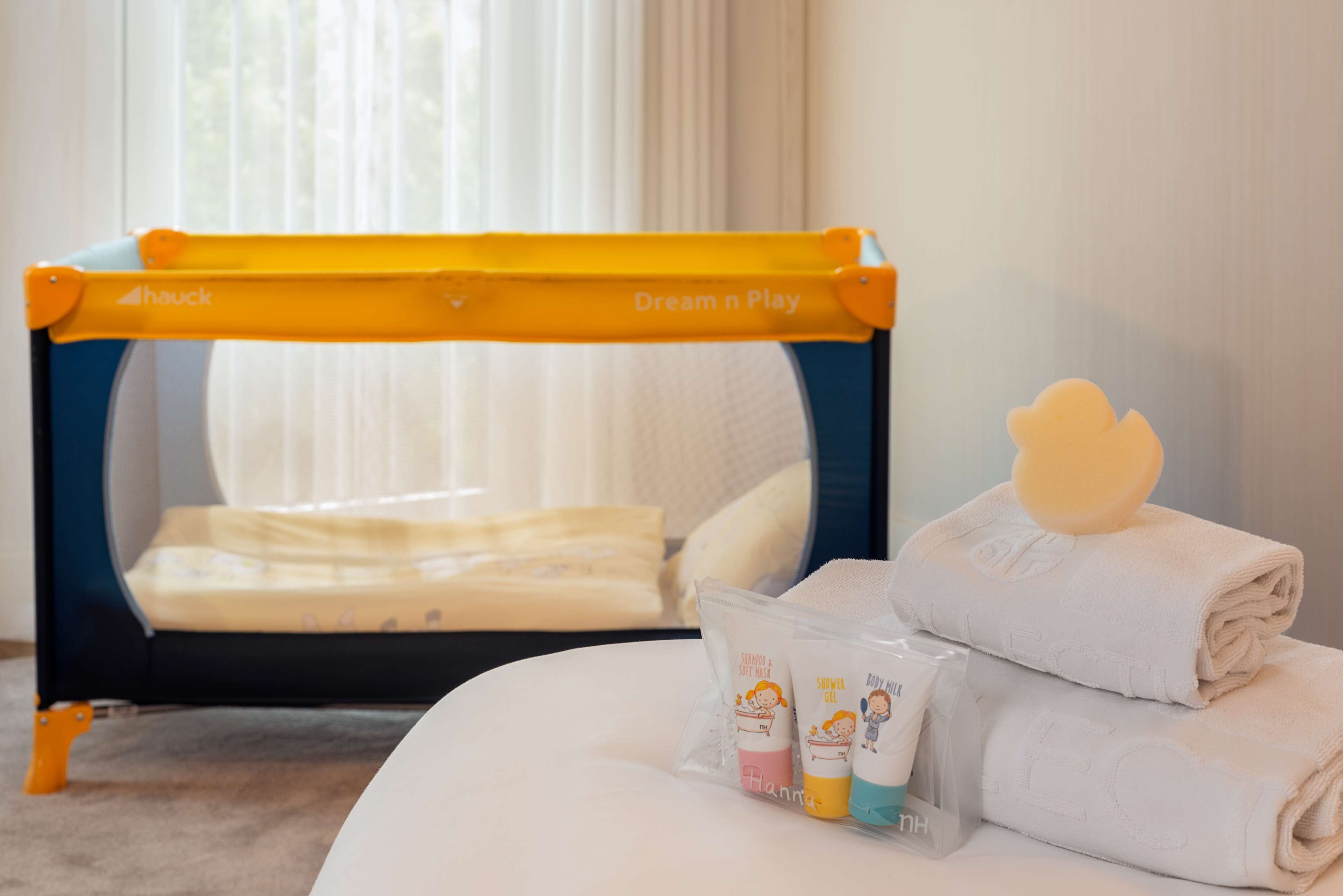 A hotel room with a bed, a small table with toiletries, and a window with curtains.