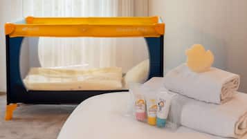 A hotel room with a bed, a small table with toiletries, and a window with curtains.