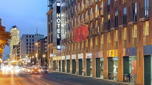 Een hotel met een opvallend 'HOTEL'-bord, meerdere balkons en een rij winkels op de begane grond.