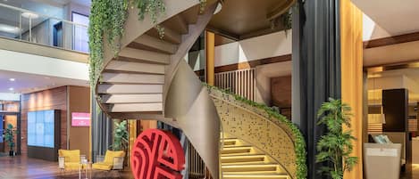 Un interior moderno con una escalera en espiral, suelo de madera y plantas de interior.