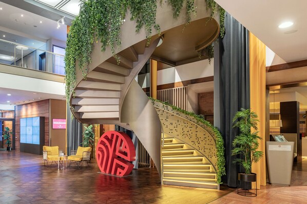A modern interior with a spiral staircase, wooden flooring, and indoor plants.