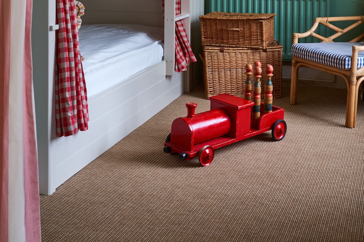 A child's room with a bunk bed, a wicker basket, a red toy train, and two framed pictures on the wall.