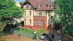 Um edifício de dois andares com telhado vermelho e paredes bege, identificado como 
