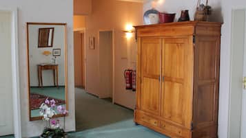 A hallway with a wooden cabinet, a mirror, and a small table with a lamp and flowers.