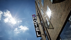 A hotel sign with a clear view of the sky and clouds.