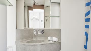 Un baño moderno con lavamanos de granito, un espejo grande y una cortina de ducha.