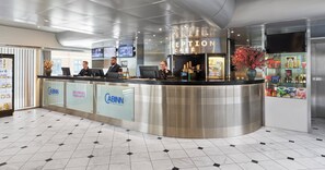 Een receptiezone met een modern design, met een receptiebalie, meerdere monitoren en een glazen scheiding waarop de naam 'Cabinn' staat.