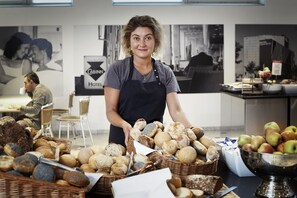 Een persoon in een keuken met verschillende soorten brood en appels.