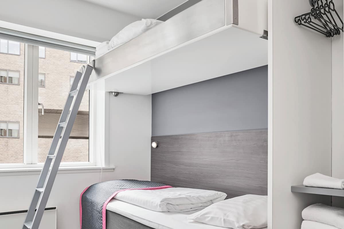 Une chambre compacte et moderne, équipée d’un lit superposé, d’un petit bureau et d’une chaise.