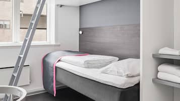 Habitación pequeña con literas, una escalera, una silla y ventana con vista a edificios.