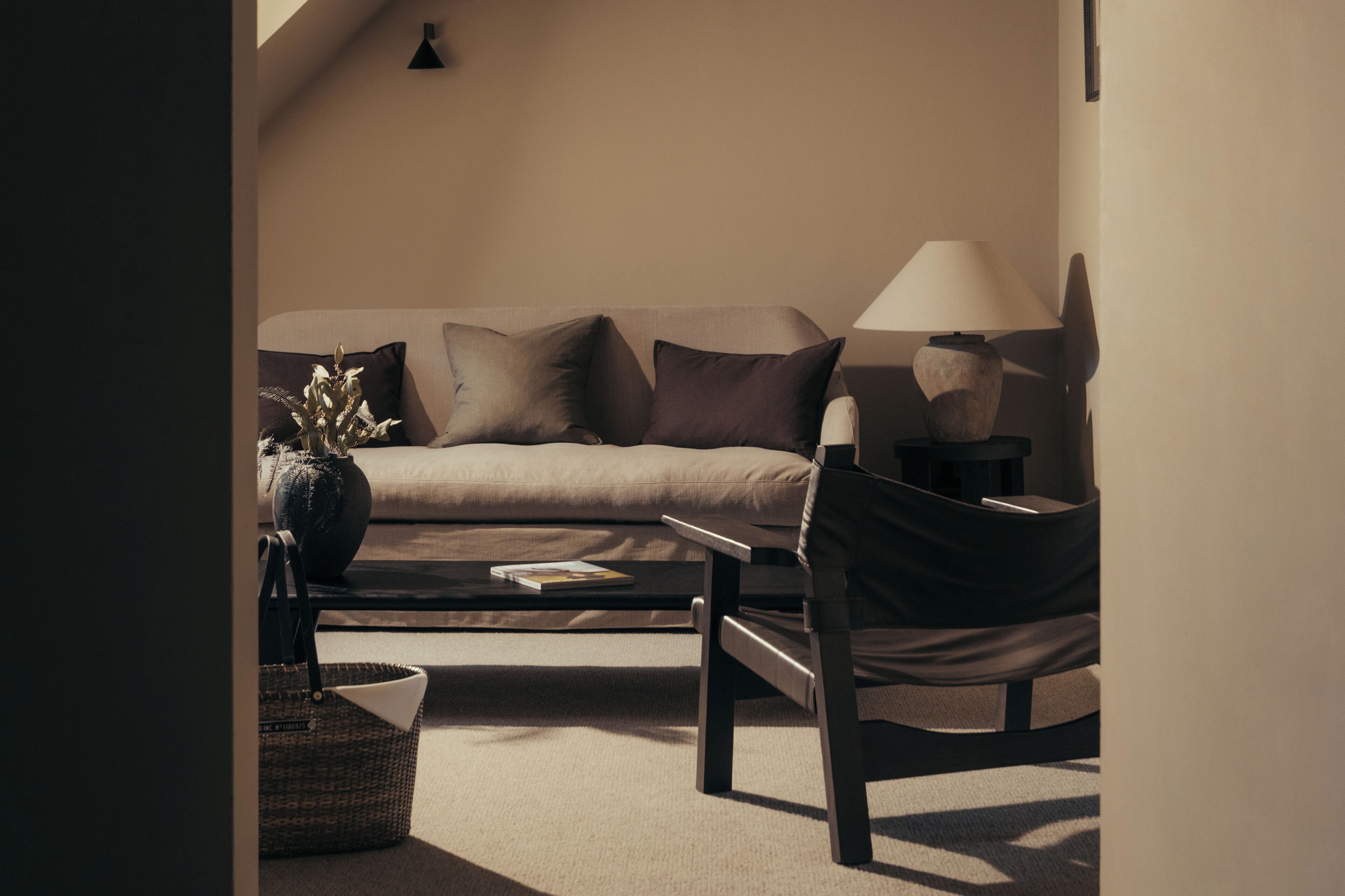 Un salon moderne avec un canapé, une table basse, une lampe et un fauteuil.